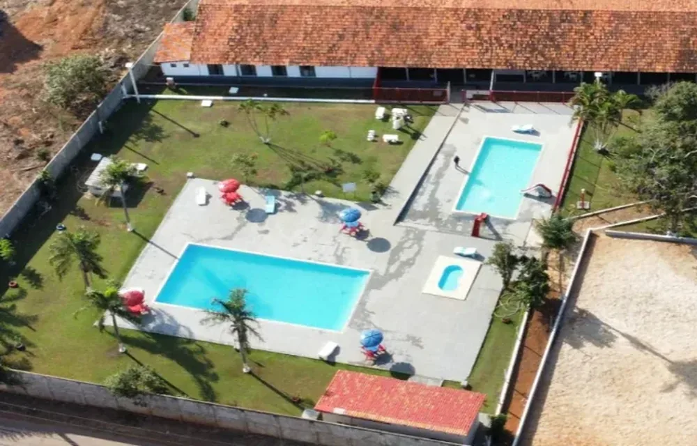 Área das piscinas da sede campestre, com espreguiçadeiras e guarda-sóis